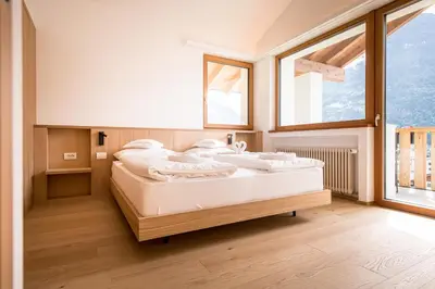 a bed in a room with a large window at Hotel Taufers in Molini di Tures