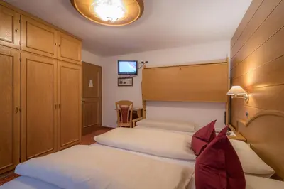 a hotel room with two beds and a tv at Garni La Vara in Corvara in Badia