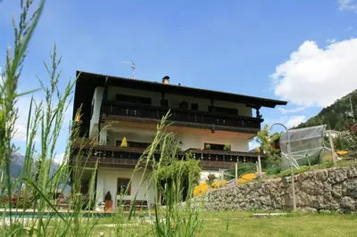 a house on a hill with a stone wall at Zimmervermietung Gröberhof in Schenna