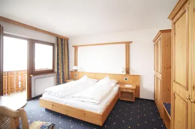 a hotel room with a bed and two windows at Naturhotel Waldheim in Anterivo