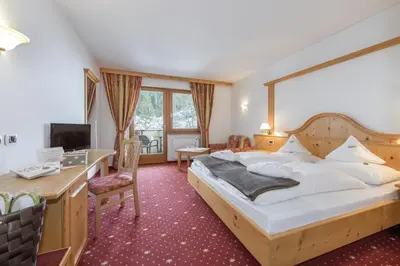 a hotel room with a large bed and a desk at Naturhotel Waldheim in Anterivo