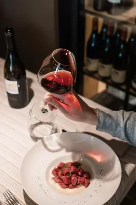 a person holding a glass of wine next to a plate of food at Hotel Belvedere in San Martino di Castrozza