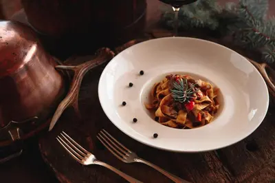 a bowl of pasta on a wooden table with forks at Hotel Belvedere in San Martino di Castrozza