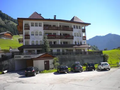 a large building with cars parked in a parking lot at Residence Barbara in Colfosco