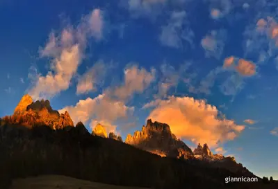 a sunset over the mountains with clouds in the sky at Residence Taufer in San Martino di Castrozza