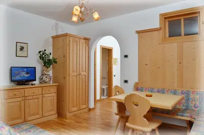 a kitchen with wooden cabinets and a table and chairs at Residence Taufer in San Martino di Castrozza