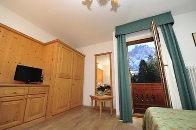 a bedroom with a bed and a television and a window at Residence Taufer in San Martino di Castrozza