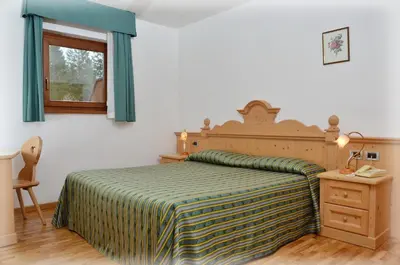 a bedroom with a bed with a green and yellow blanket at Residence Taufer in San Martino di Castrozza