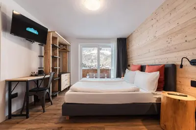 a bedroom with a bed and a desk and a television at Hotel Sassleng in Canazei