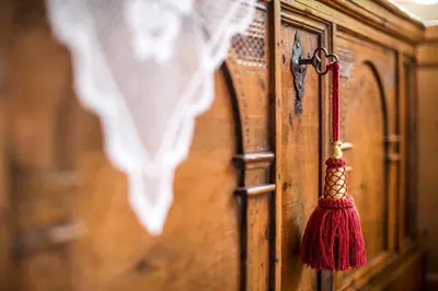 a red tassel hanging from a wooden door at Hotel Sassleng in Canazei