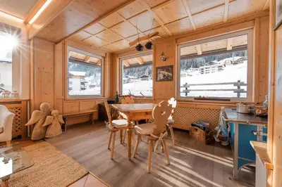 a dining room with a table and chairs and windows at Hotel Sassleng in Canazei