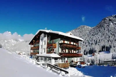 a large building in the snow in the mountains at Hotel Sassleng in Canazei