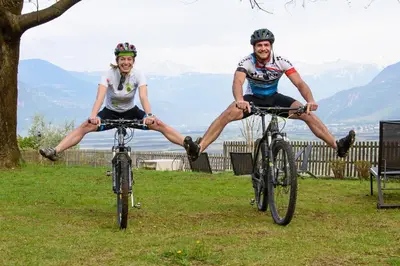 two people sitting on their bikes in the grass at Hotel Sigmundskron in Appiano sulla Strada del Vino