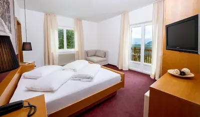a hotel room with a bed and a television at Hotel Sigmundskron in Appiano sulla Strada del Vino