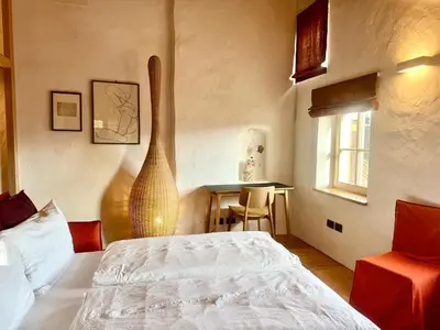 a bedroom with a bed and a table and a window at Ansitz Jenner in Appiano sulla Strada del Vino