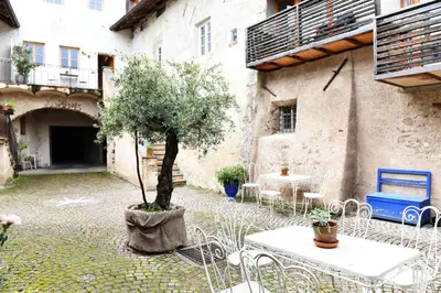 a courtyard with a tree and tables and chairs at Ansitz Jenner in Appiano sulla Strada del Vino