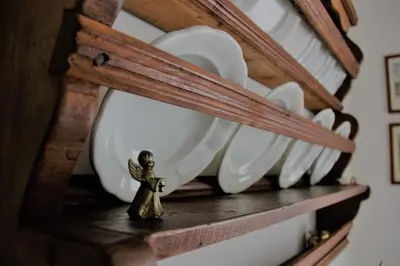 a small figurine on a shelf with white plates at Da Rinota in Alta Val di Non in Malosco