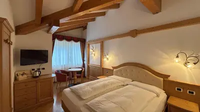 a bedroom with a large bed and a television at Hotel Mirabello - Slow Hotel Benessere in Fiera di Primiero