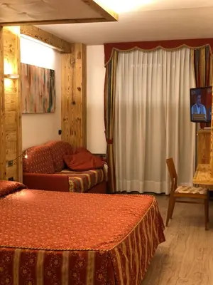 a hotel room with two beds and a couch at Hotel Mirabello - Slow Hotel Benessere in Fiera di Primiero