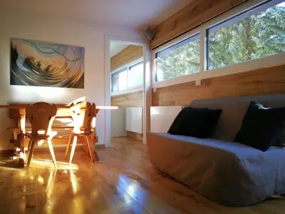 a living room with a couch and a table and windows at Luce Delle Dolomiti con navetta e sala giochi in Mazzin
