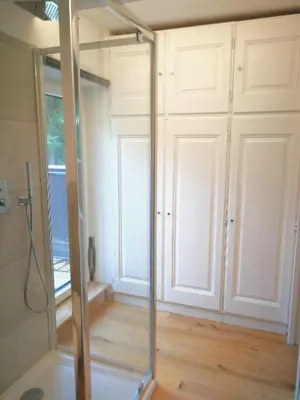 a glass shower in a bathroom with white cabinets at Luce Delle Dolomiti con navetta e sala giochi in Mazzin