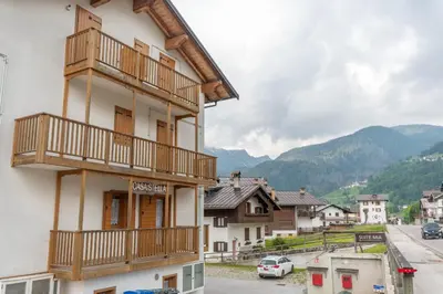 a building with wooden balconies in a village at Casa Stella in Falcade