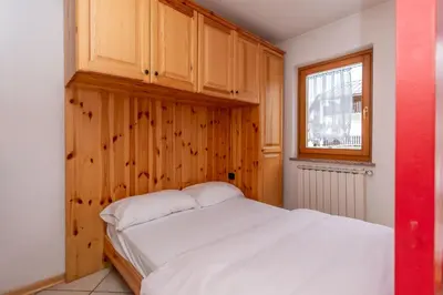 a bedroom with a white bed and a window at Casa Stella in Falcade