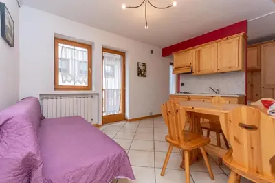 a bedroom with a bed and a table and a kitchen at Casa Stella in Falcade