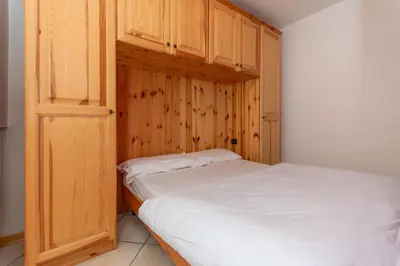 a small bedroom with a bed and wooden cabinets at Casa Stella in Falcade