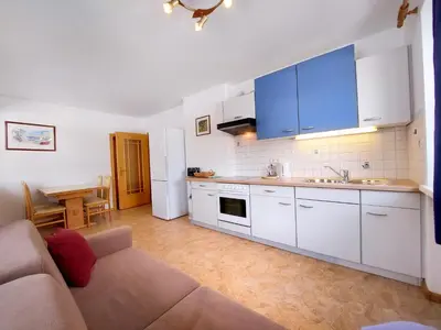 a living room with a couch and a kitchen at Garni Hotel Melissa in Castelrotto