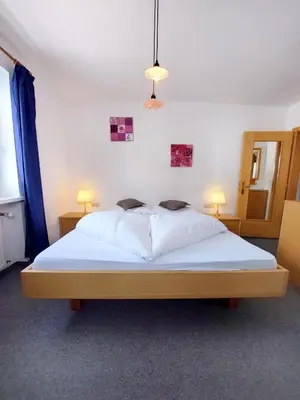 a bedroom with a large white bed with two lamps at Garni Hotel Melissa in Castelrotto