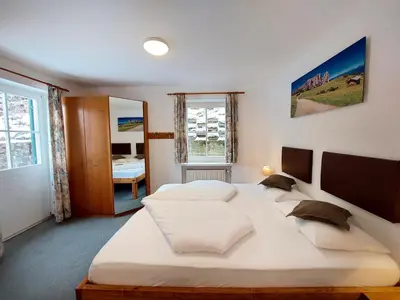 a bedroom with two large beds and a window at Garni Hotel Melissa in Castelrotto