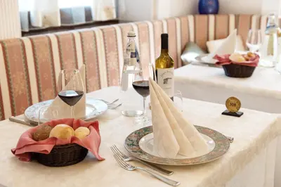 a table with glasses of wine and a plate of food at Albergo Belvedere in Fiera di Primiero