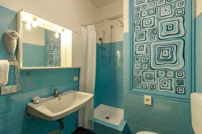 a blue tiled bathroom with a sink and a shower at Albergo Belvedere in Fiera di Primiero