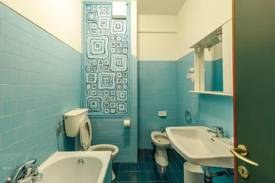 a blue tiled bathroom with a toilet and a sink at Albergo Belvedere in Fiera di Primiero
