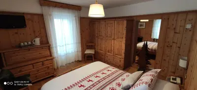 a bedroom with a bed and a television in a room at Hotel Villa Gaia in Cortina dʼAmpezzo