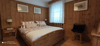 a bedroom with a bed with wooden walls and a window at Hotel Villa Gaia in Cortina dʼAmpezzo