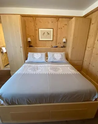 a large bed in a room with wooden walls at Hotel Villa Gaia in Cortina dʼAmpezzo