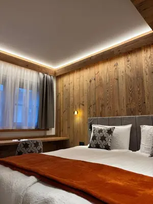 a bedroom with a large bed with two chairs at Affittacamere Villa Sole in Fiera di Primiero