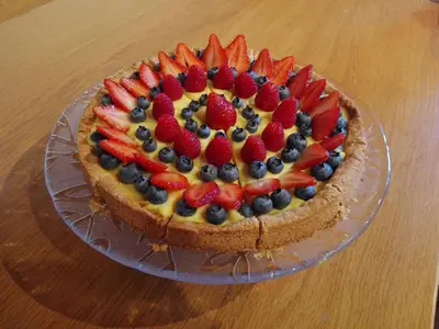 a cake with strawberries and blueberries on a glass plate at Affittacamere Villa Sole in Fiera di Primiero