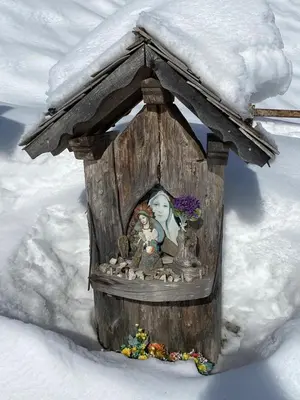 a small wooden bird house with a statue in the snow at Albergo Lozen in Canale San Bovo