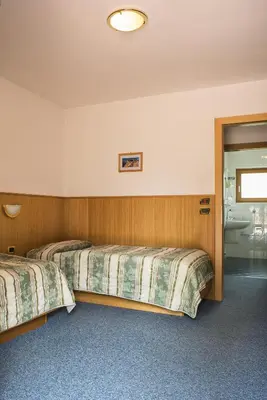 a hotel room with two beds and a bathroom at Hotel Sonne Sole in Vigo di Fassa