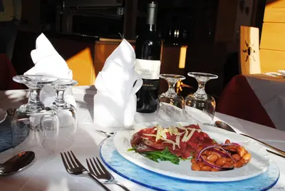 a plate of food on a table with a bottle of wine at Hotel Sonne Sole in Vigo di Fassa