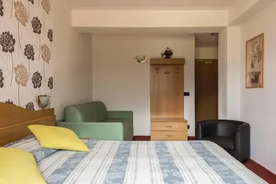a bedroom with a bed and a chair at Hotel Sonne Sole in Vigo di Fassa