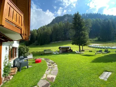a backyard with a grassy yard with a table and chairs at Chalet Romy - Ap Saslonch in Pramauron