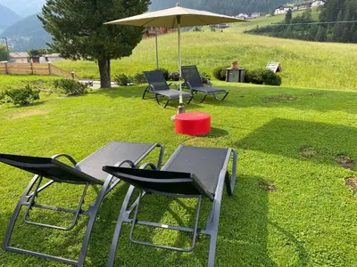 two chairs and a table and an umbrella in the grass at Chalet Romy - Ap Saslonch in Pramauron