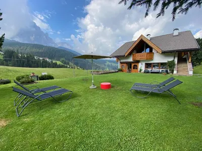 two chairs and an umbrella in front of a building at Chalet Romy - Ap Saslonch in Pramauron
