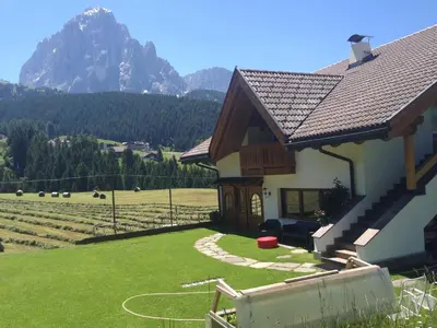 a house with a field and mountains in the background at Chalet Romy - Ap Saslonch in Pramauron