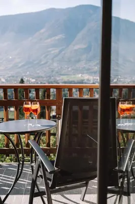 two tables with glasses of wine on a balcony at Feldhof Schenna in Schenna