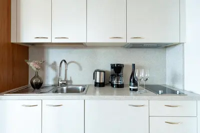 a kitchen with white cabinets and a sink at Feldhof Schenna in Schenna